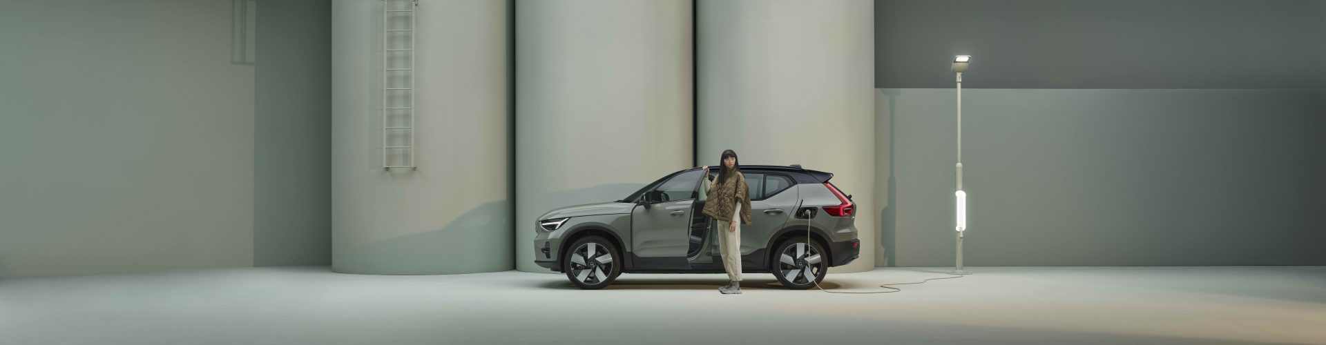 Tjej står vid grön Volvo EX40 som laddar