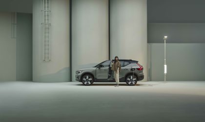 Tjej står vid grön Volvo EX40 som laddar