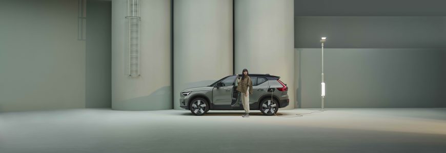 Tjej står vid grön Volvo EX40 som laddar